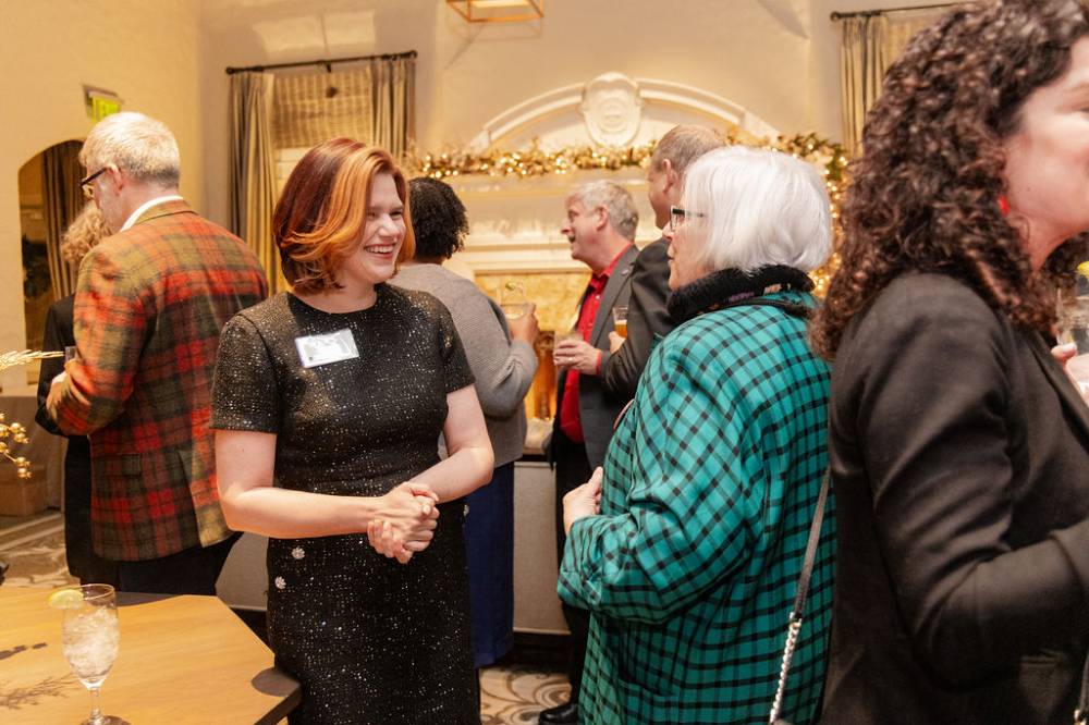 Laura Aikens smiling and chatting with woman at party